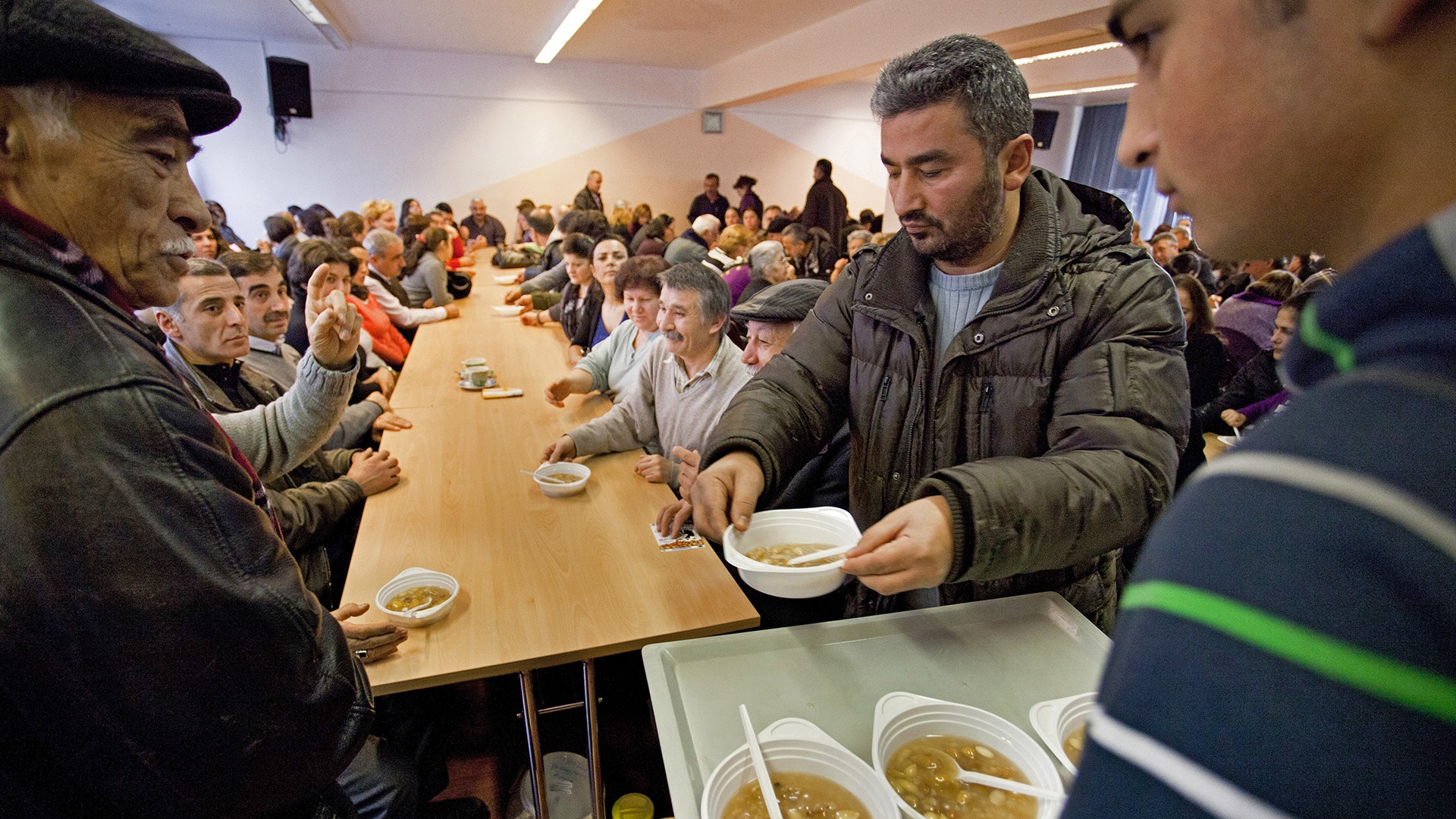 Alevitische Männer geben Asure-Suppe an Gemeindemitglieder aus