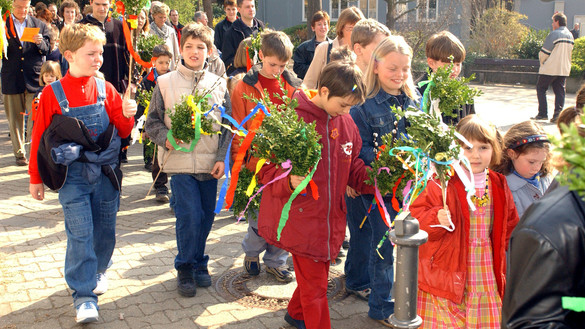 Palmsonntagsfeier in Mainz. Kinder und Erwachsene laufen am Palmsonntag mit Palmsträußen zur Messe ins katholische Pfarrzentrum Mainz-Laubenheim.