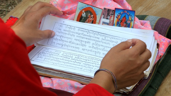 Buddhistische Schrift mit kleiner Glocke im Hintergrund.