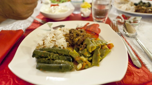 Weißer Teller mit Fleisch, Reis, Weinblättern und Bohnen bei einem Essen zum Fastenbrechen an einem Abend im Ramadan.