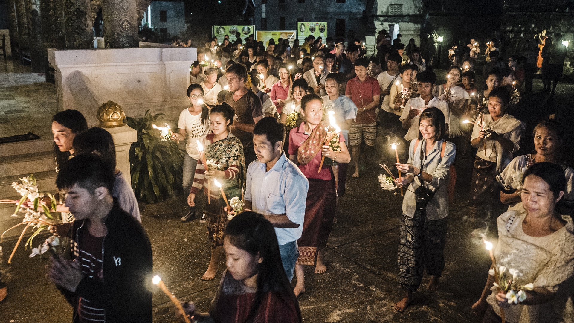 Buddhistische Gläubige laufen mit Kerzen durch die Straßen von Luang Prabang in Laos