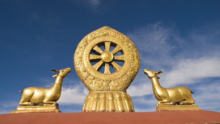 Ein goldenes Dharma-Rad auf einem roten Dach eines buddhistischen Tempels.