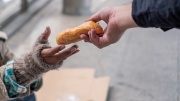 Obdachlose Person bekommt Brötchen überreicht