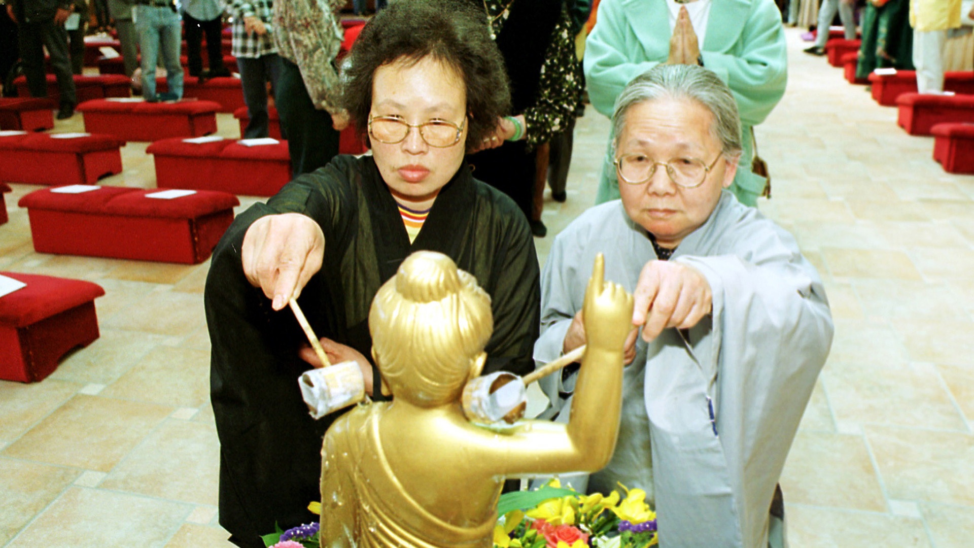 Die Buddhastatue wird mit kleinen Kellen von den Schultern abwärts gewaschen. 