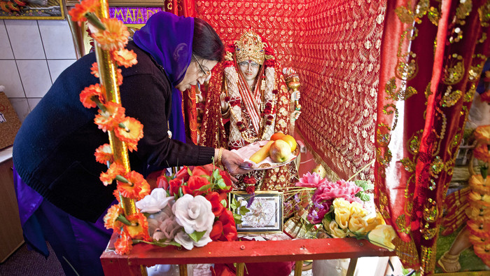 Eine Inderin dekoriert den kleinen Hausaltar
