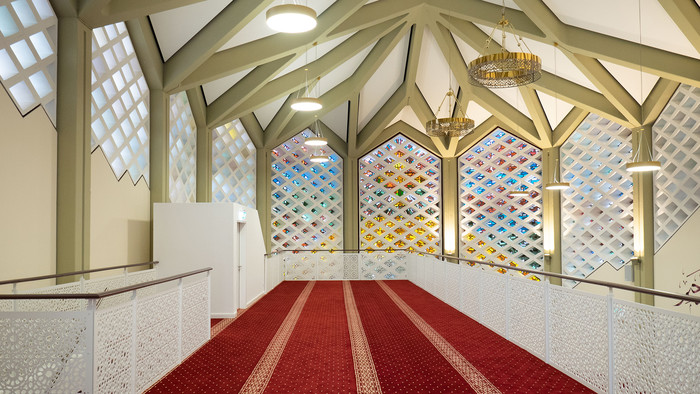 Innenraum der Al-Nour Moschee in Hamburg mit weißen Wänden und rotem Teppichboden