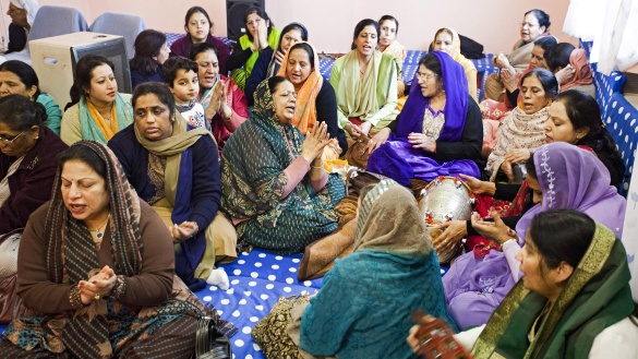 Hindu-Frauen sitzen zusammen und einige singen.
