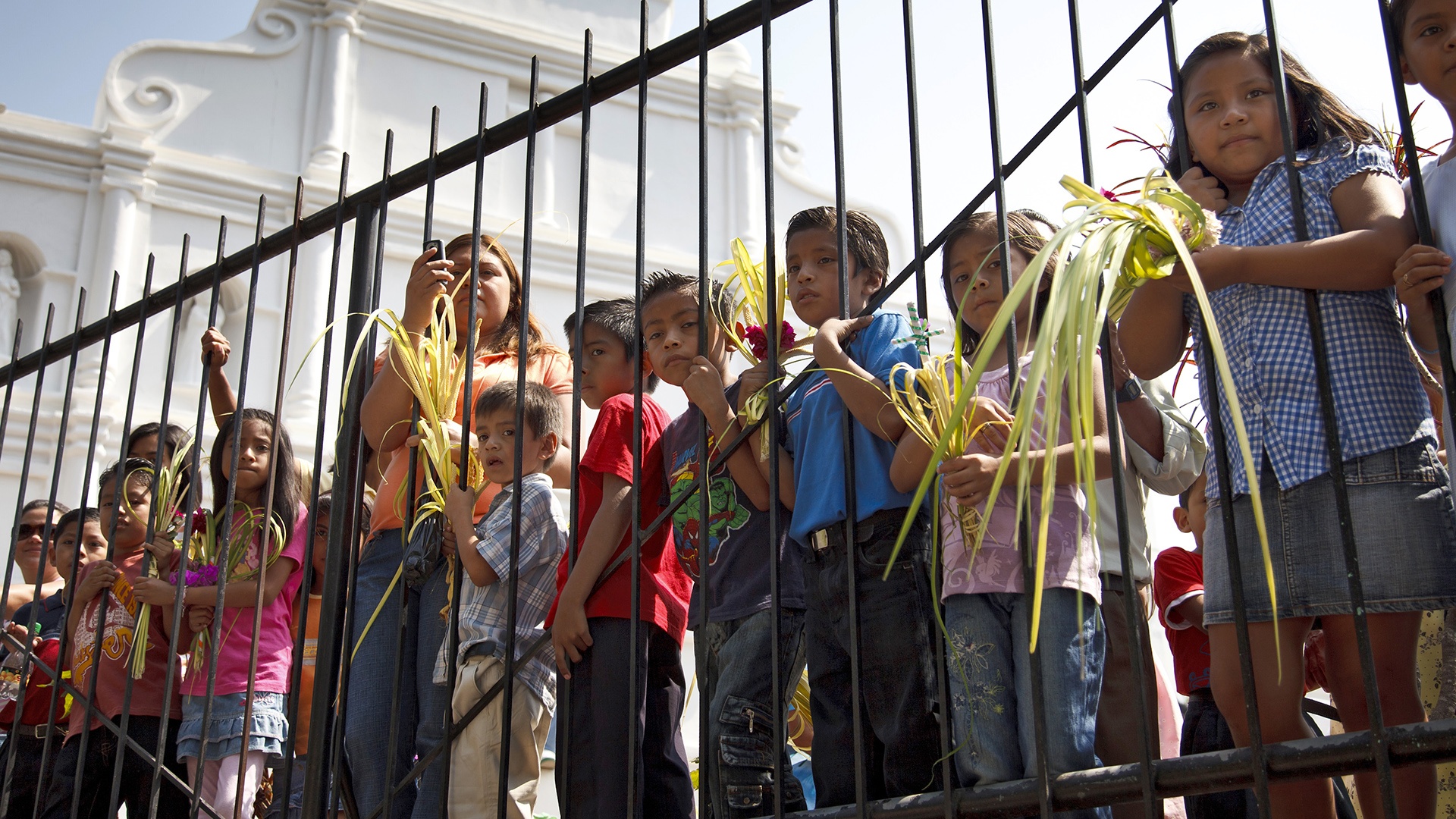 Kinder hinter einem Zaun auf Palmsonntagsprozession in Panchimalco, El Salvador