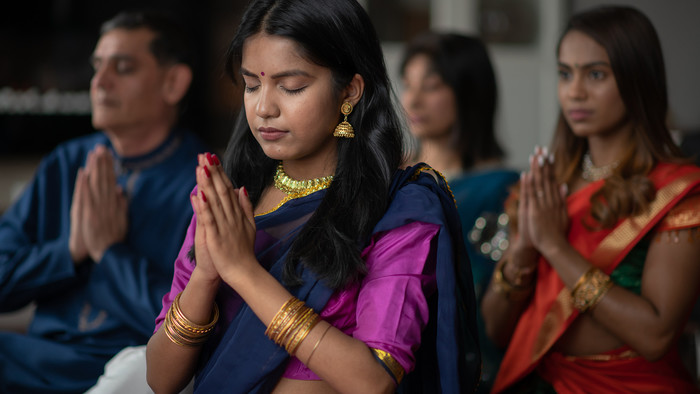 Ein indisches Mädchen betet mit aneinandergelegten Händen.