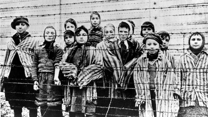 Kinder hinter einem Stacheldraht des Konzentrationslagers Auschwitz-Birkenau während seiner Befreiung.