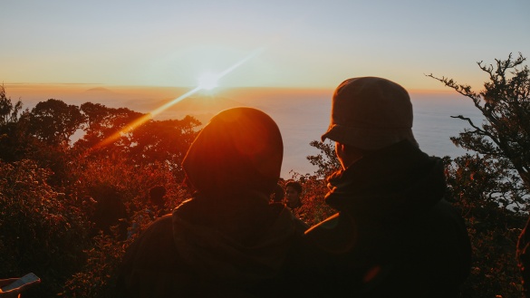 Zwei Personen blicken in die Ferne bei Sonnenuntergang