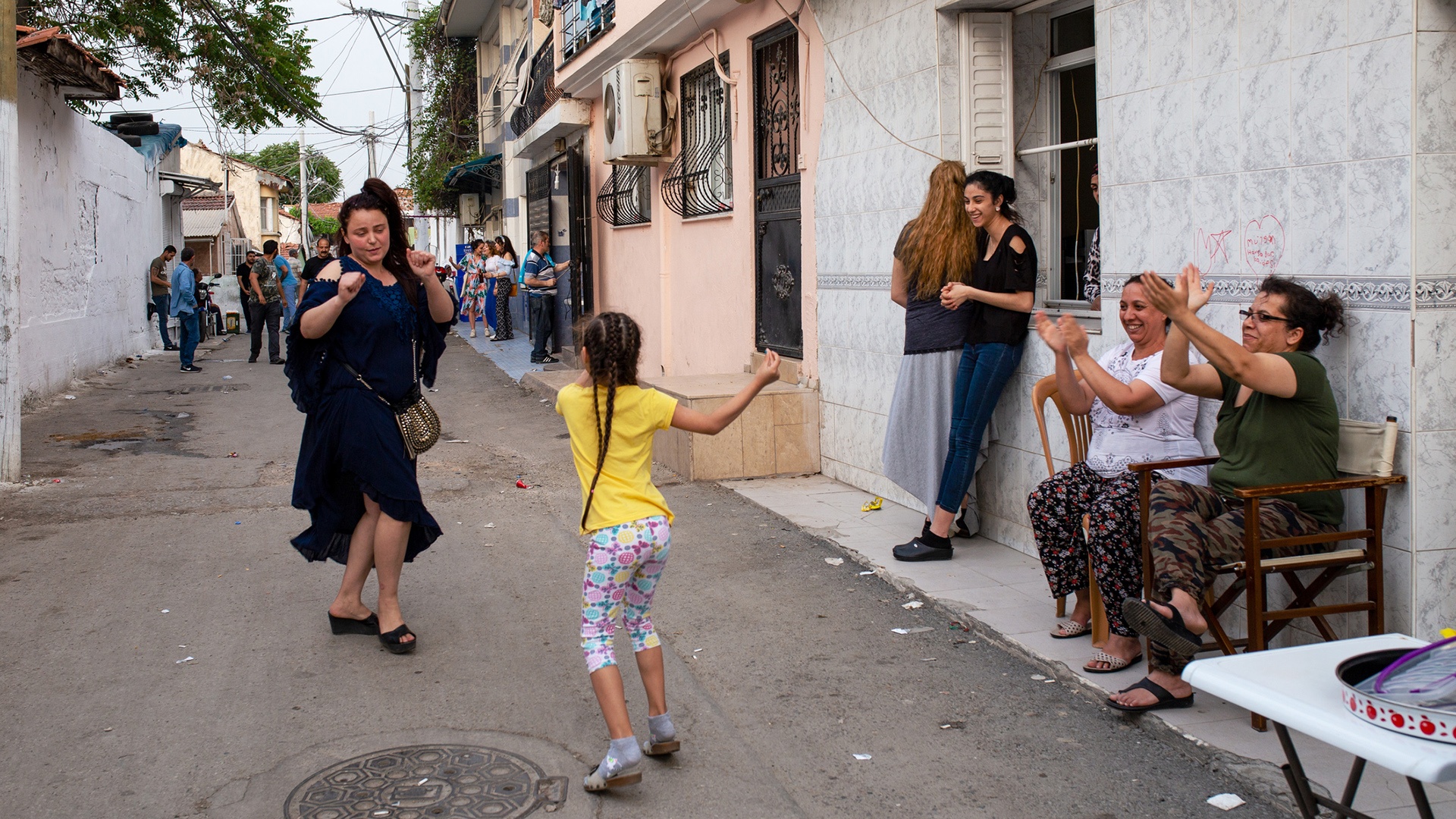 Menschen klatschen, während ein Mädchen und eine Frau auf der Straße tanzen