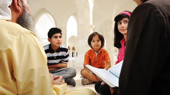 Muslimische Kinder und ein Lehrer mit dem Koran.