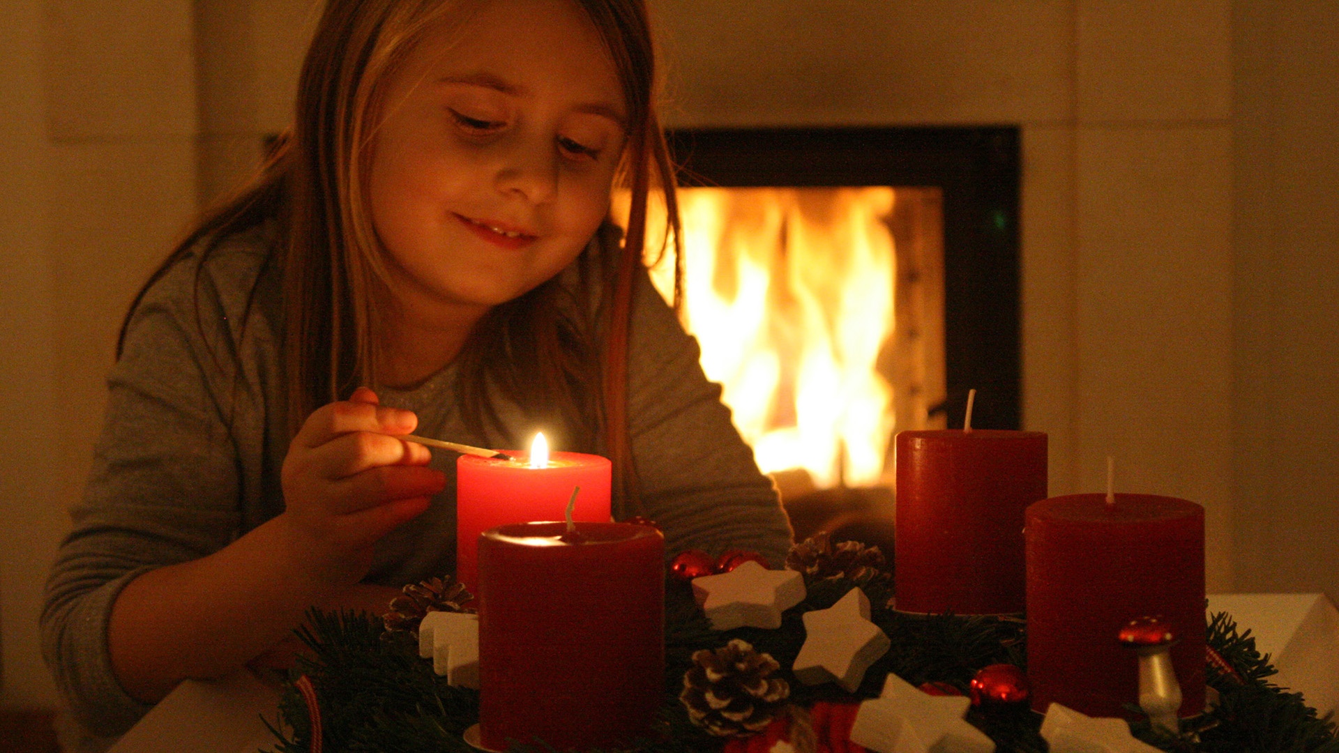 Kind zündet erste Kerze des Adventskranzes an