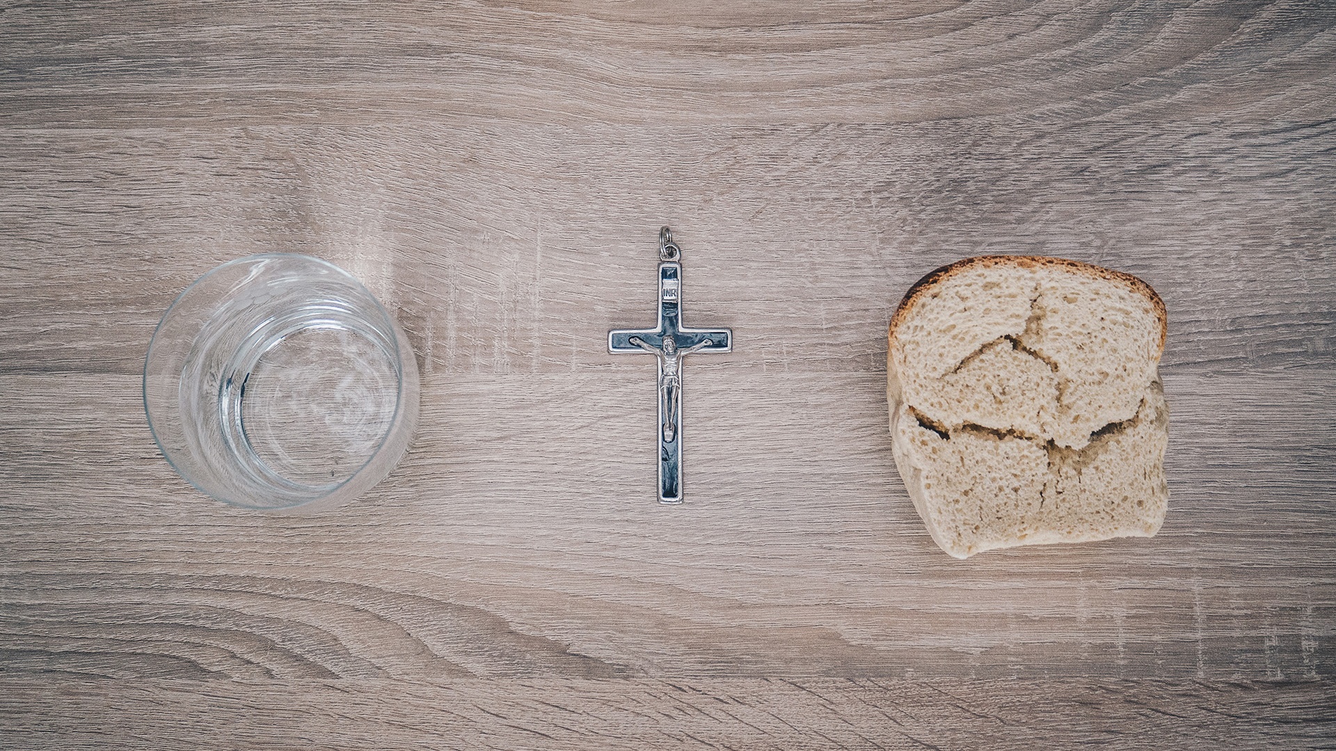 Wasser, Kreuz und Brot liegen auf einem Tisch