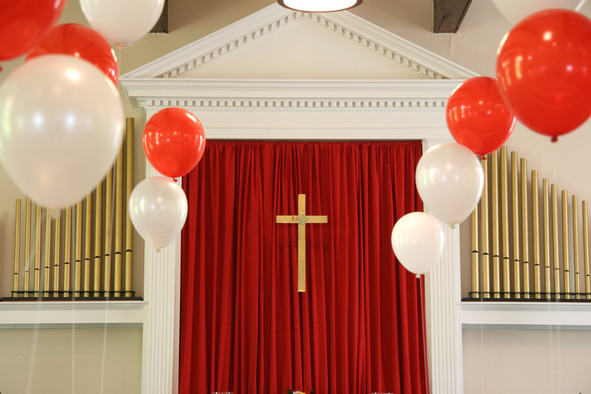 Kreuz umgeben von weißen und roten Luftballons