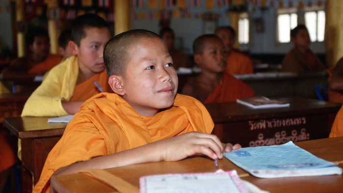 Buddhistischer Novize in orangefarbener Kleidung im Unterricht.