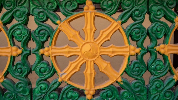 Dharma-Rad in orange, umgeben von grünen Mustern.