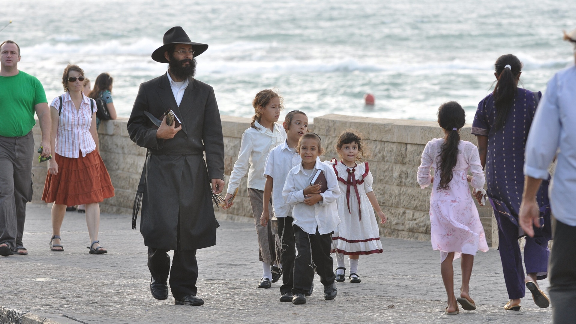 Erwachsene und Kinder laufen auf einer Straße nahe des Strandes in Tel Aviv