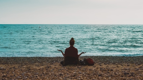 Eine Frau meditiert mit Blick auf das Meer
