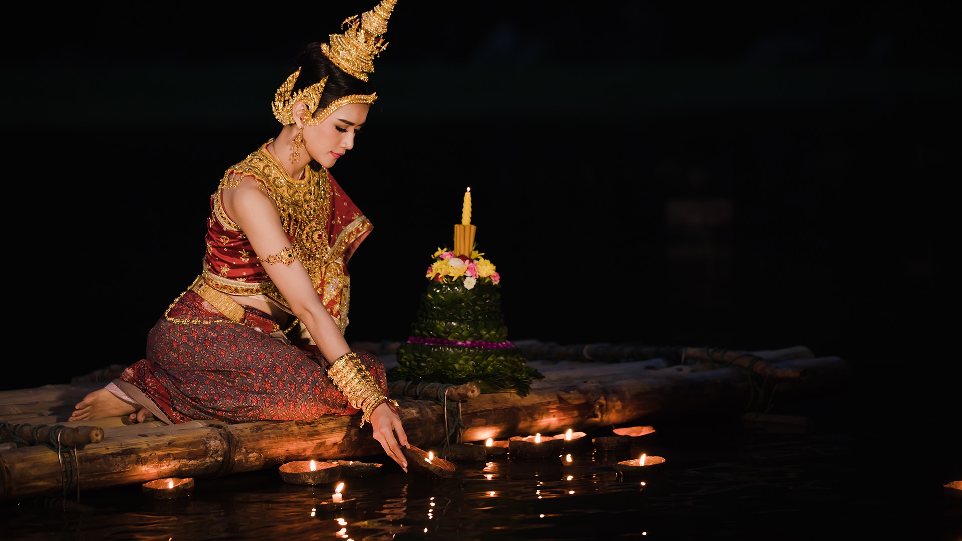 Thailänderin lässt dekoriertes Floß ins Wasser gleiten