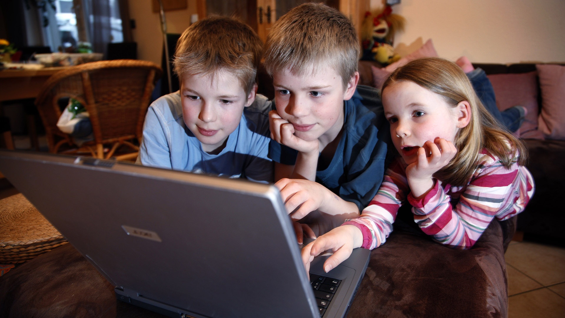 drei Kinder sitzen vor einem Laptop 
