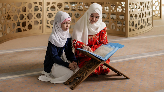 zwei Frauen lesen den Koran auf der Rahle