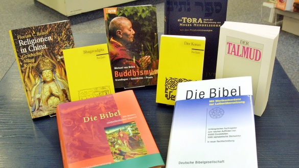 Bücher über Religionen in China, den Buddhismus, Bhagavadhgita, Talmud, Tora, Bibel und Koran stehen und liegen auf einem Tisch