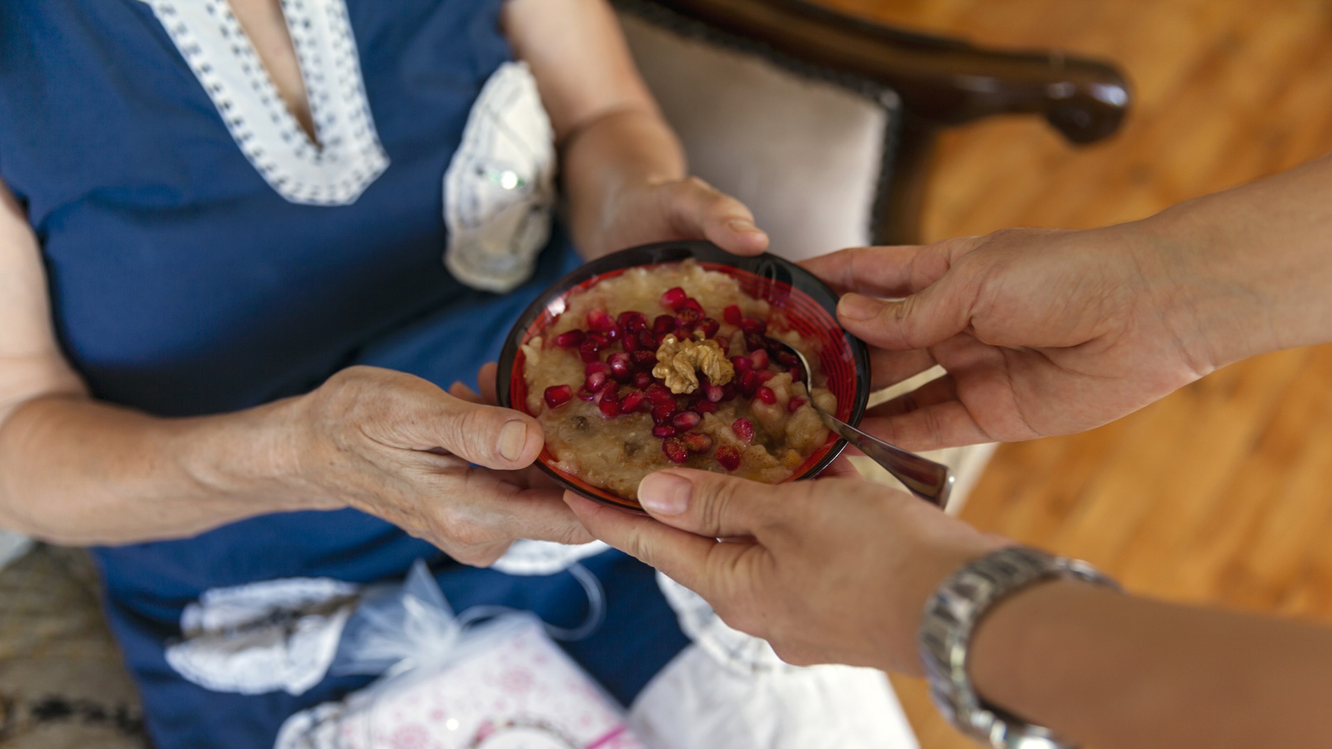 Frau reicht Aschura-Suppe an eine ältere Frau