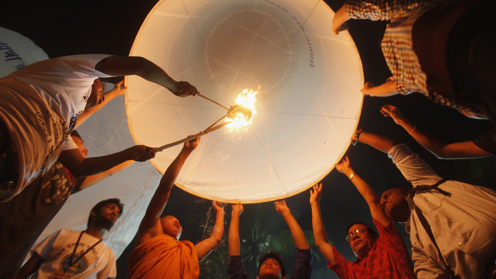 buddhistische Gläubige lassen einen großen Heißluftballon in den Nachthimmel aufsteigen