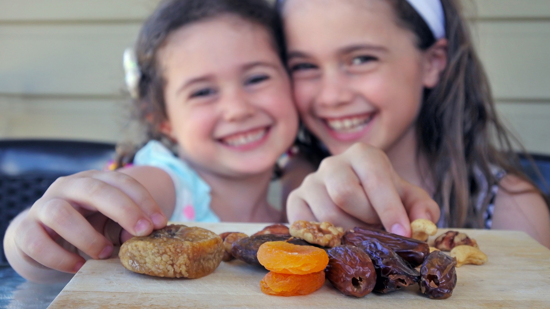 Zwei Mädchen essen getrocknetes Obst an Tu biSchwat