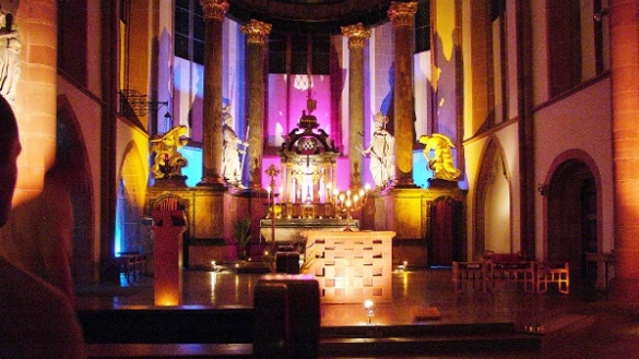 Blick auf den bunt beleuchteten Altarraum der katholischen St. Quintinskirche in Mainz.