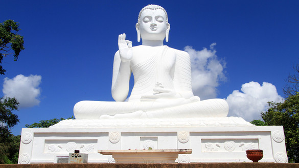 Weißer Buddha vor blauem Himmel.