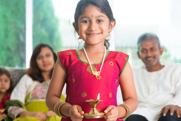 Ein indisches Mädchen mit einem Opferlicht in den Händen, im Hintergrund die Mutter, der Vater und eine kleine Schwester.
