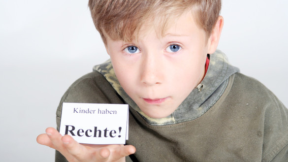 Ein Junge hält ein Schild auf seiner Hand auf dem steht: Kinder haben Rechte!