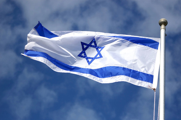 Flagge von Israel mit Davidstern vor blauem Himmel.