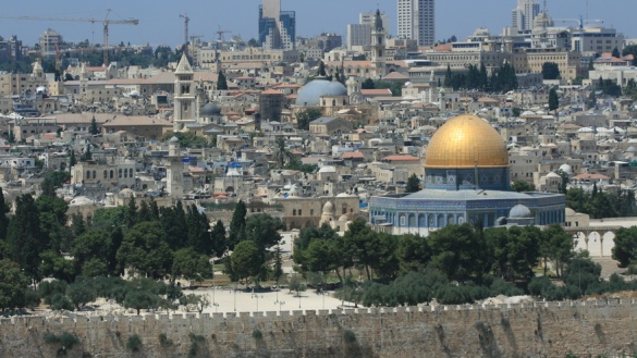 Blick von oben auf die Stadt Jerusalem mit der goldenen Kuppel des Felsendoms und vielen Hochhäusern im Hintergrund.