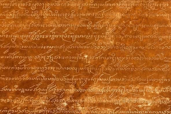 Messingfarbene Metallplatte mit eingravierten Pali-Schriftzeichen.