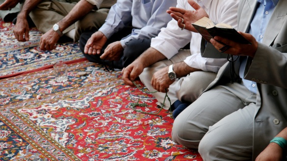 Blick auf knieende Muslime, die in einer Moschee beten.