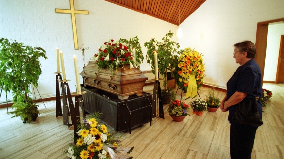 Ein mit Blumengestecken geschmückter Sarg in einer Trauerhalle.
