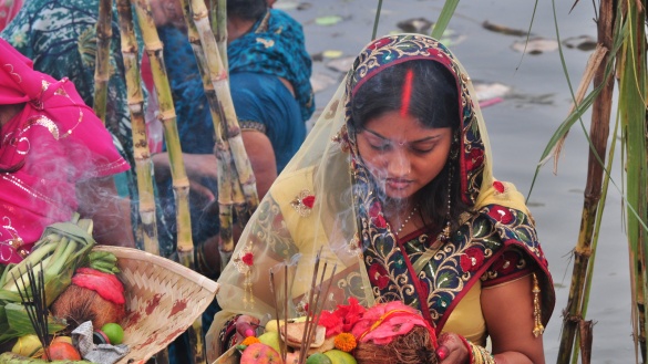 Eine Inderin mit einer Opferschale, gefüllt mit buntem Obst und brennenden Räucherstäbchen.