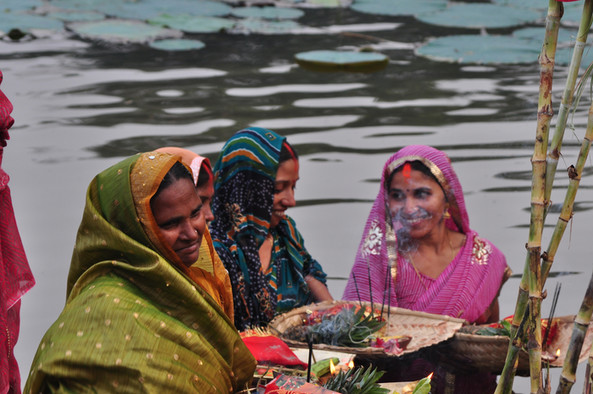 Indische Frauen in bunten Gewändern bei einer Puja am Ganges.