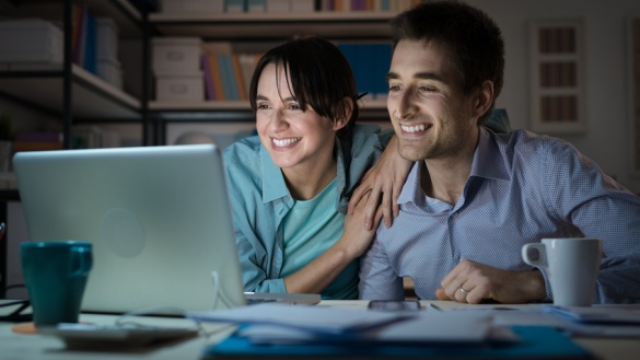 Ein junges Paar schaut gemeinsam auf einen Laptop.