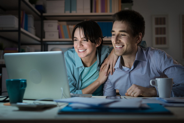Ein junges Paar schaut gemeinsam auf einen Laptop.