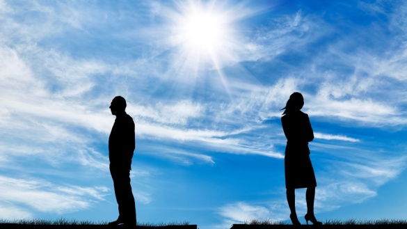 Silhouette eines Mannes und einer Frau, getrennt durch einen Spalt in der Erde vor blauem Himmel