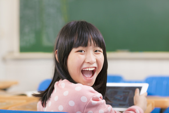 Ein lachendes Mädchen mit einem Tablet-Computer in der Hand.