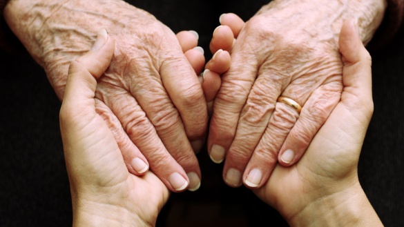 Zwei junge Hände halten zwei alte Hände.