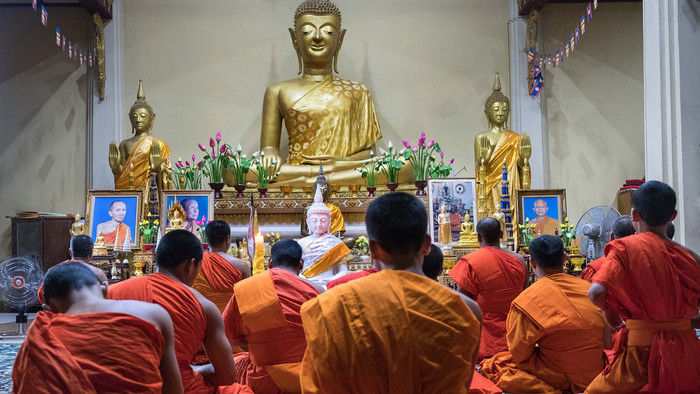 Buddhistische Mönche vor einer goldenen Buddha-Statue