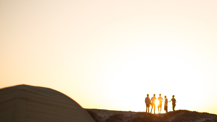 Gruppe von Menschen in der Ferne vor einer untergehenden Sonne